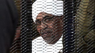 In this file photo taken in August 2019, Sudan's deposed military ruler Omar al-Bashir looks on from a defendant's cage during the opening of his corruption trial in Khartoum.