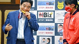 4 agosto 2021: il sindaco di Nagoya Takashi Kawamura, a sinistra, morde la medaglia d'oro olimpica di Miu Goto, a destra, dalla squadra di softball giapponese,