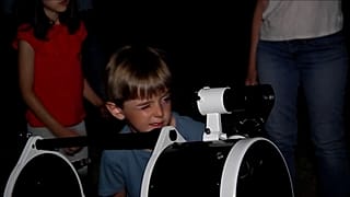 Un niño mira por un telescopio 