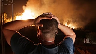 ينظر رجل إلى حريق غابة بالقرب من قرية أربا ناث إراثن في تيزي وزو بمنطقة القبائل الجبلية- 11 آب / أعسطش 2021