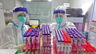 Workers handle swab samples for COVID-19 test at a hospital lab in Yantai in eastern China