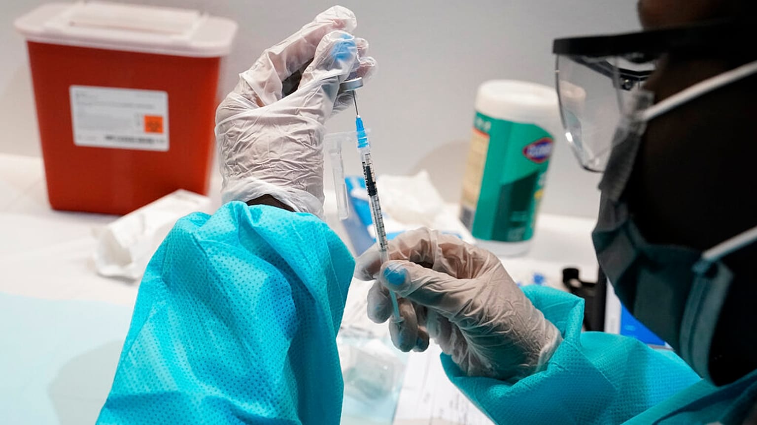 a health care worker fills a syringe with the Pfizer COVID-19 vaccine