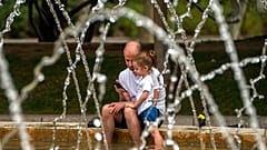 Un padre y su hija se refrescan en una fuente de Madrid, España