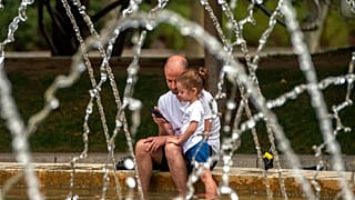 Un padre y su hija se refrescan en una fuente de Madrid, España