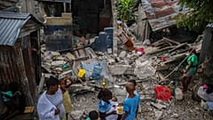 Eine Familie in Les Cayes frühstückt vor ihrem zerstörten Heim