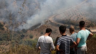 سكان يشاهدون حريقًا بالقرب من قرية توجة بمنطقة القبائل شرقي الجزائر العاصمة، الجمعة 13 أغسطس 2021