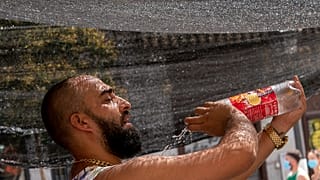 A vendor of a stall in the Rastro flea market tries to cool himself by pouring water over his body during a heatwave in Madrid