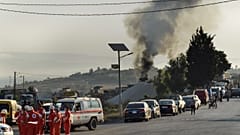 متطوعو الصليب الأحمر اللبناني يتجمعون في شارع بجوار مكان انفجار صهريج وقود في قرية تليل، شمال لبنان.