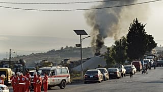 متطوعو الصليب الأحمر اللبناني يتجمعون في شارع بجوار مكان انفجار صهريج وقود في قرية تليل، شمال لبنان.
