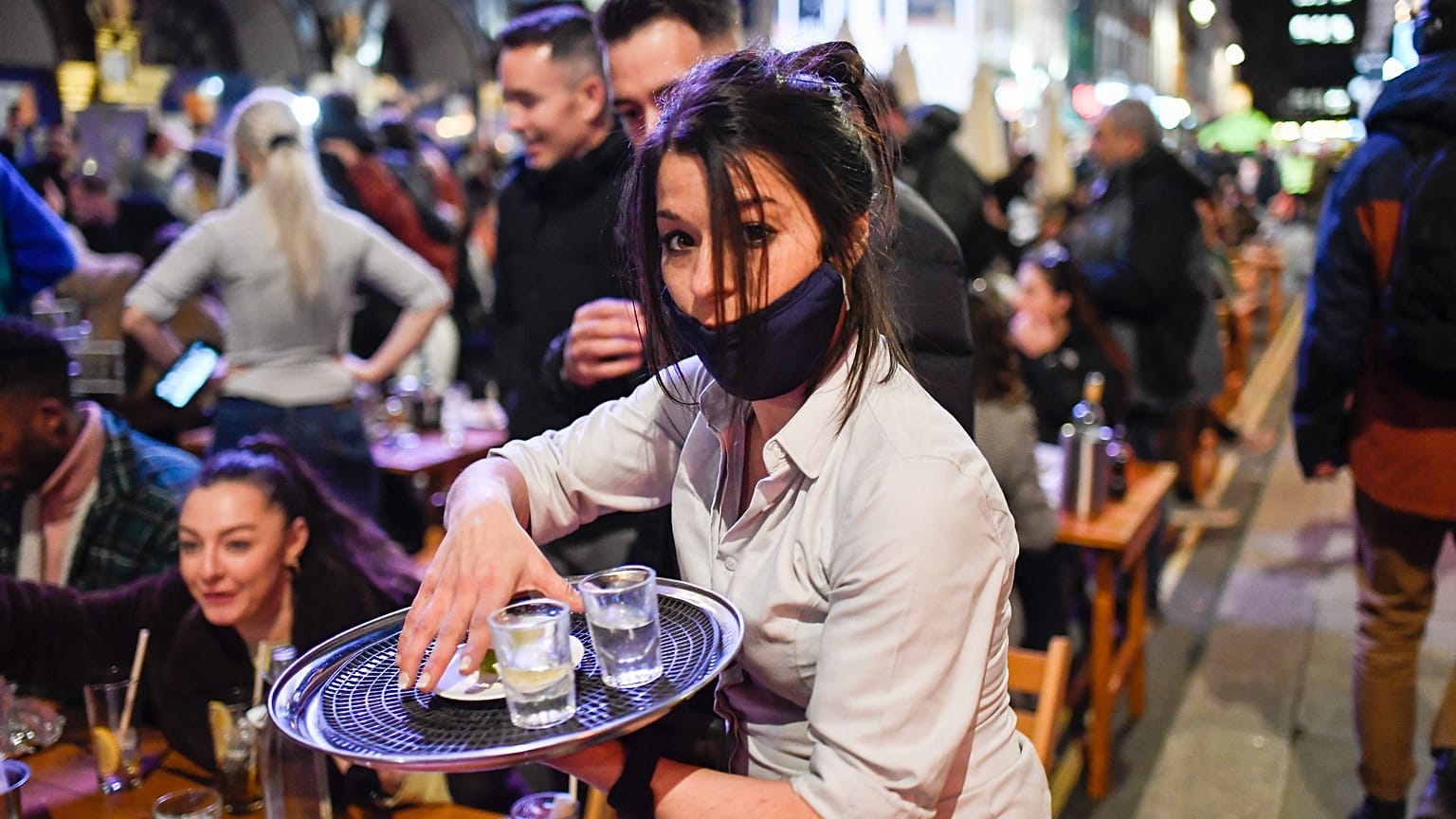 A waitress serves drinks at tables outside a pub in Soho, London as COVID-19 restrictions are eased on April 12, 2021.