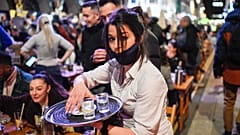 A waitress serves drinks at tables outside a pub in Soho, London as COVID-19 restrictions are eased on April 12, 2021.
