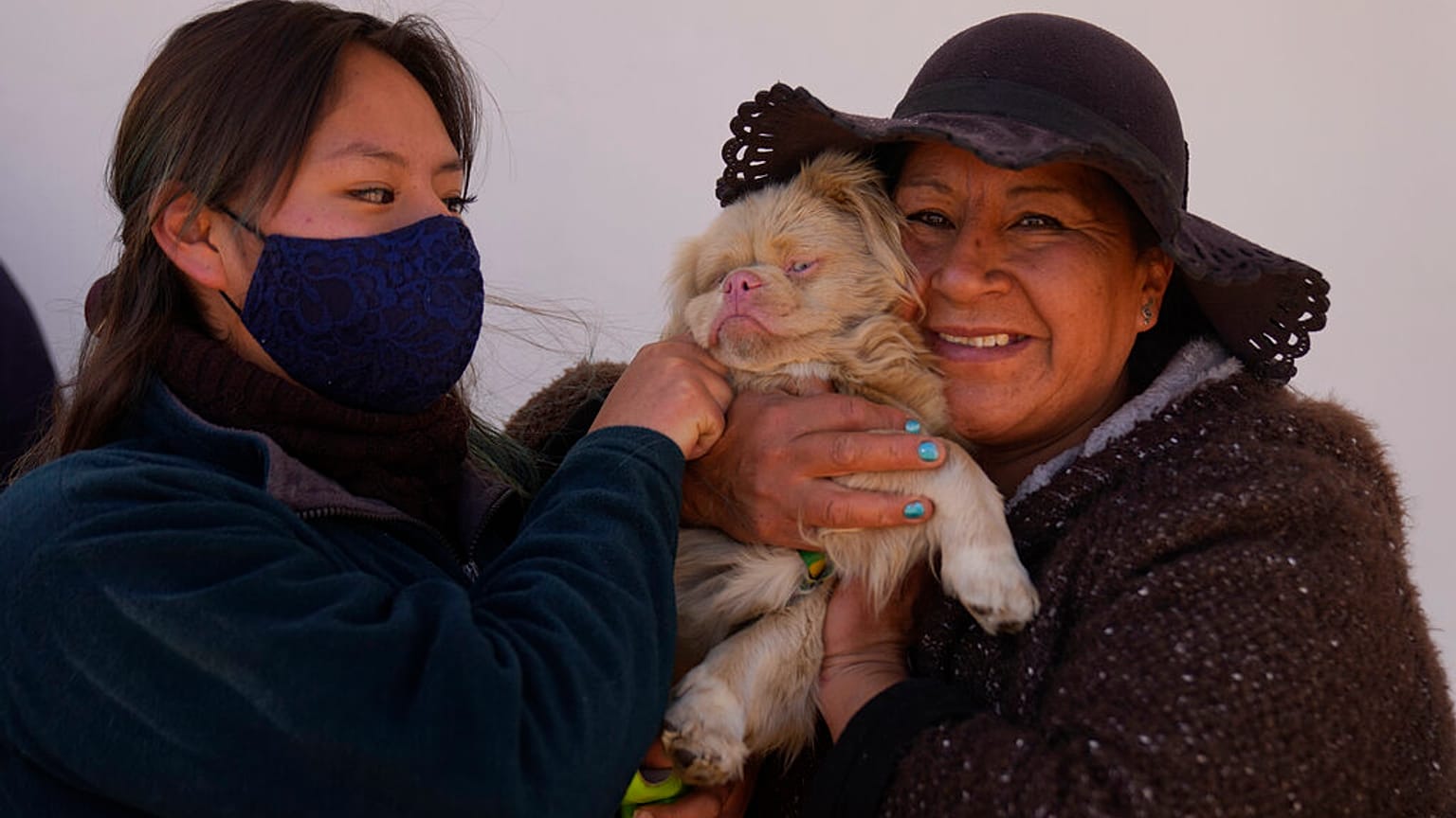 Deux femmes et leur chien assistent à la messe organisée pour célébrer la saint Roch, le saint patron des chiens, à El Alto, en Bolivie, le 16 août 2021. 