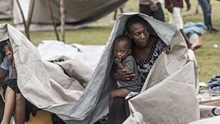 People gather after spending the night outside in the aftermath of the earthquake, facing the severe inclement weather of Tropical Storm Grace.