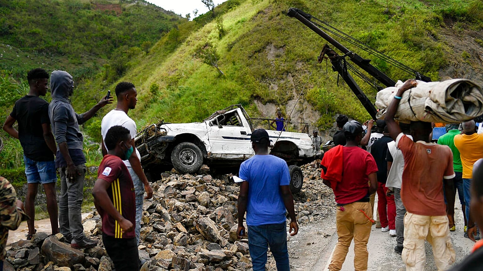 A crane removes a truck from a pile of rocks after landslides triggered by a 7.2-magnitude earthquake that hit four days prior in River Glass, Haiti, Wednesday, Aug. 18, 2021.