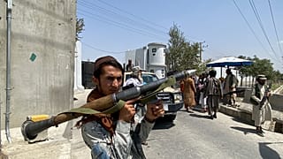 Un guerrigliero talebano di guardia davanti alla sede del ministero dell'Interno a Kabul, 17 agosto 2021