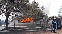 A firefighter extinguish the fire to a house during a wildfire in Thea area some 60 kilometers 