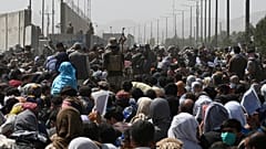 أفغان يتجمعون على جانب طريق بالقرب من الجزء العسكري من مطار كابول في 20  آب / أغسطس 2021،على أمل الفرار من البلاد بعد سيطرة طالبان على أفغانستان.