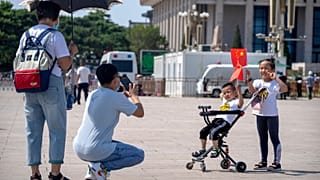 Children hold Chinese flags as they pose for a photo at Tiananmen Square in Beijing, on June 22, 2021. 