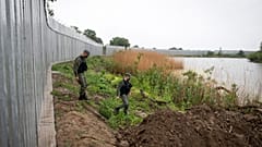 In this May 21, 2021, file photo, policemen patrol alongside a steel wall at Evros river, near the village of Poros, at the Greek -Turkish border, Greece. 