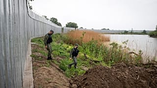 In this May 21, 2021, file photo, policemen patrol alongside a steel wall at Evros river, near the village of Poros, at the Greek -Turkish border, Greece.