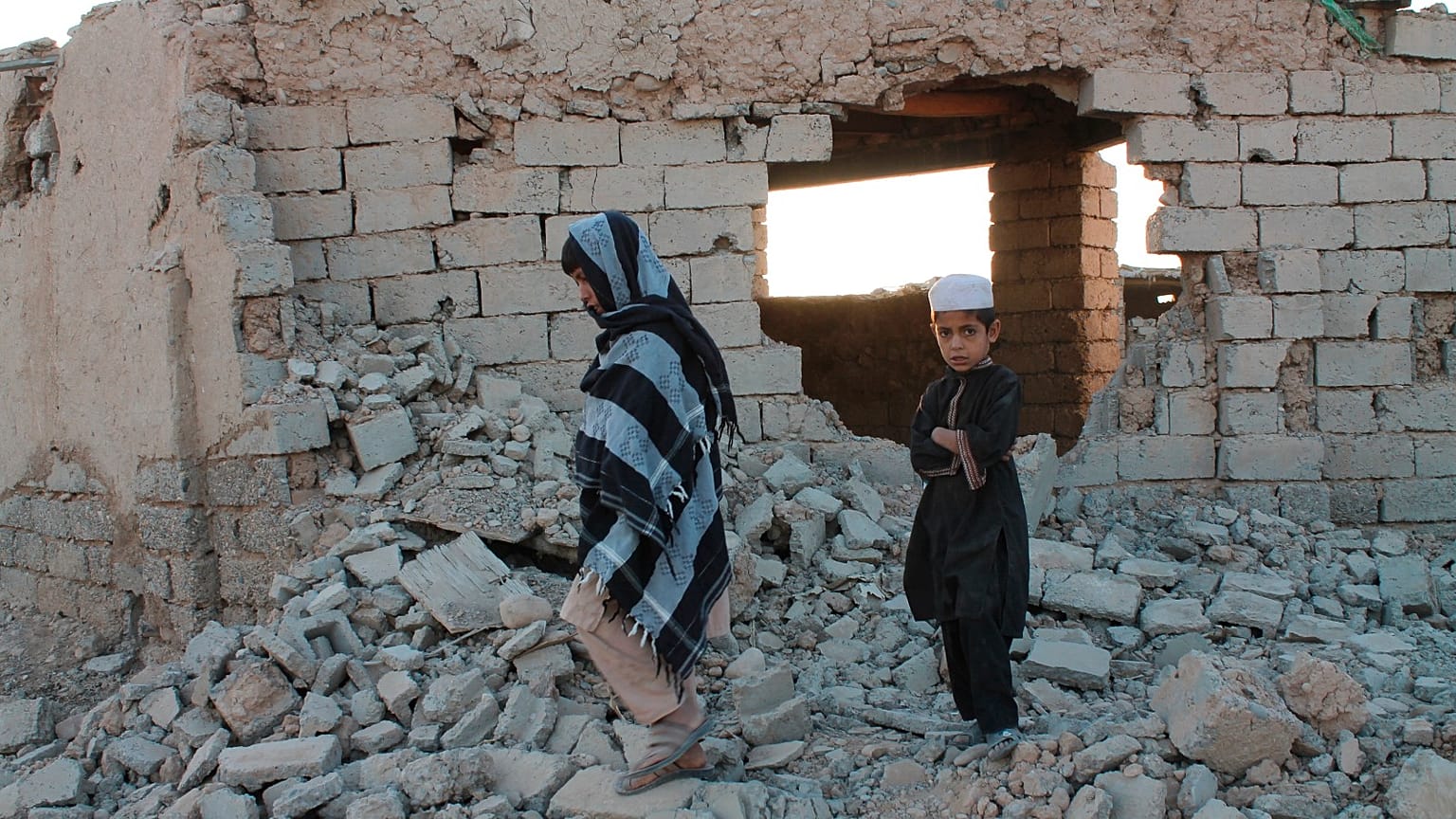 Afghan boys walk near a damaged house after airstrikes two weeks ago during a fight between government forces and the Taliban in Lashkar Gah.