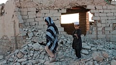 Afghan boys walk near a damaged house after airstrikes two weeks ago during a fight between government forces and the Taliban in Lashkar Gah.