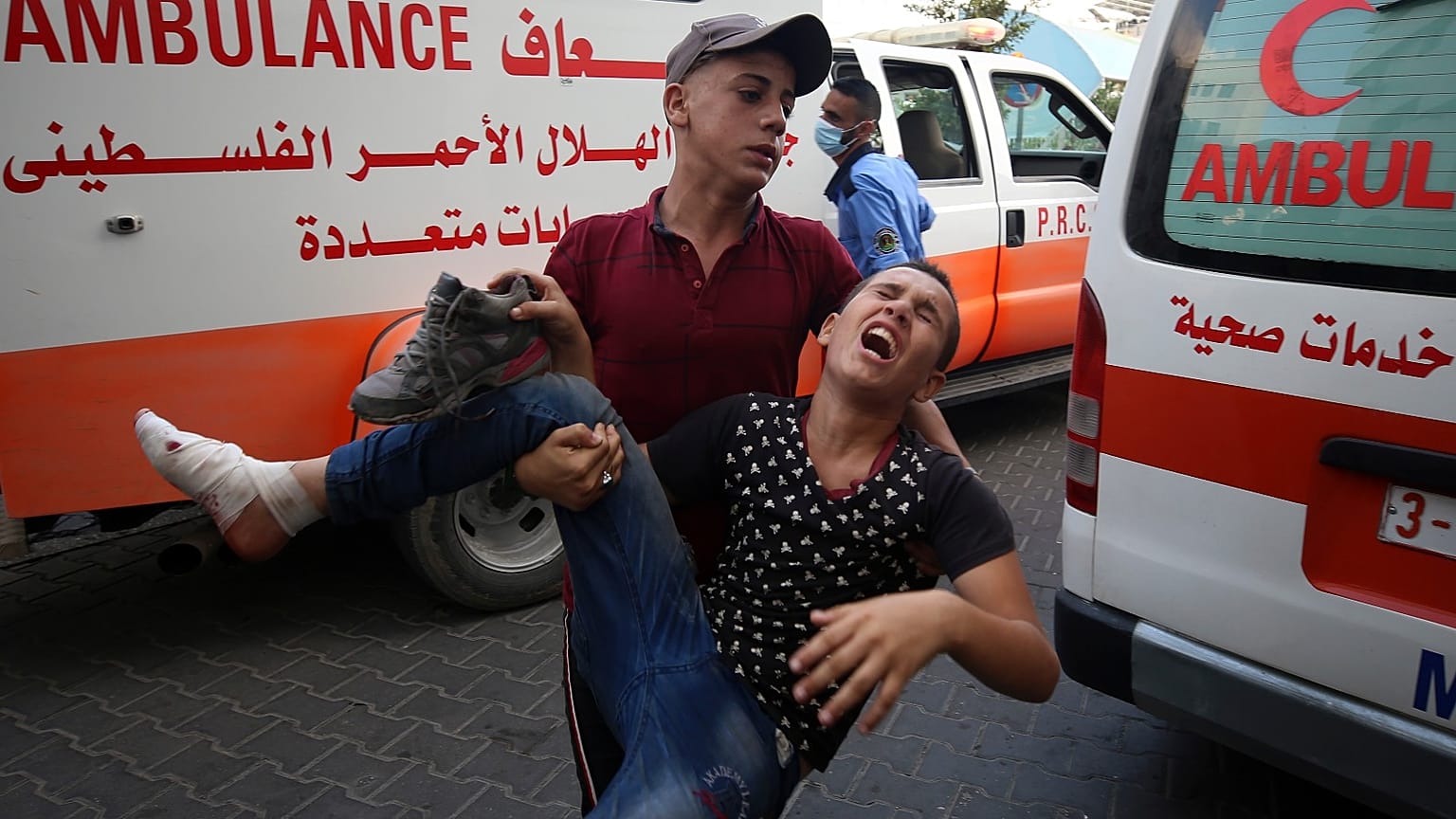 A protestor helps a wounded youth, who was shot by Israeli troops in his foot during a protest at the Gaza Strip's border with Israel.