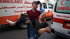 A protestor helps a wounded youth, who was shot by Israeli troops in his foot during a protest at the Gaza Strip's border with Israel.