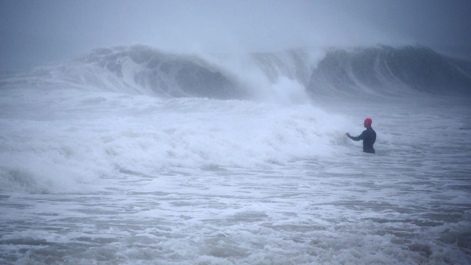 Matt Prue, from Stonington, Conn., walks out into the Atlantic Ocean to body surf the waves from Tropical Storm Henri as it approaches Westerly, R.I., Sunday, Aug. 22, 2021.