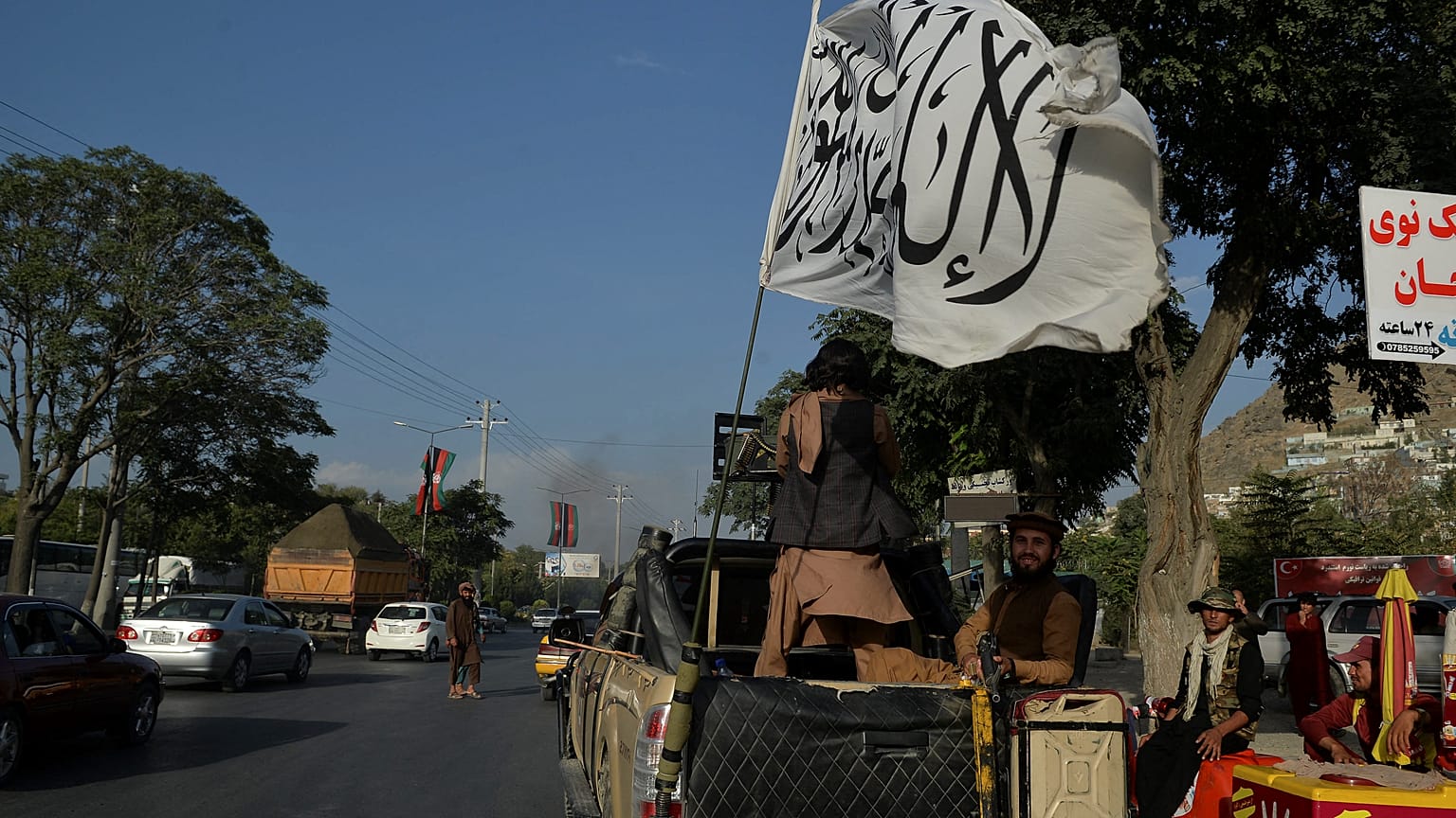 Taliban fighters travel on a vehicle mounted with the Taliban flag in the Karte Mamorin area of Kabul on August 22, 2021