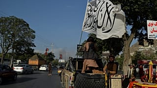 Taliban fighters travel on a vehicle mounted with the Taliban flag in the Karte Mamorin area of Kabul on August 22, 2021