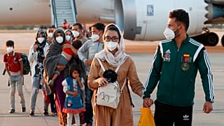 Afghan Paralympic wheelchair basketball player Nilofar Bayat, centre left and her husband arrive at Torrejon military base just outside Madrid, Spain, Friday, Aug. 20, 2021