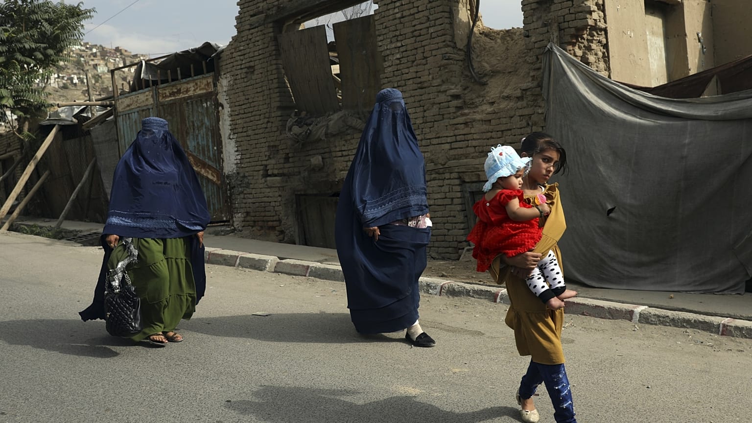 Burkába öltözött nők és gyerekek sétálnak egy kabuli utcán