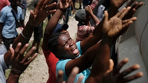 Earthquake victims reach for water being handed out during a food distribution