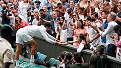 Serbia's Novak Djokovic presents his tennis racquet to a young fan after winning the men's singles final of the Wimbledon Tennis Championships in London, July 11, 2021.