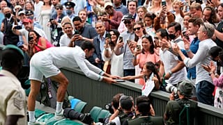 Serbia's Novak Djokovic presents his tennis racquet to a young fan after winning the men's singles final of the Wimbledon Tennis Championships in London, July 11, 2021.