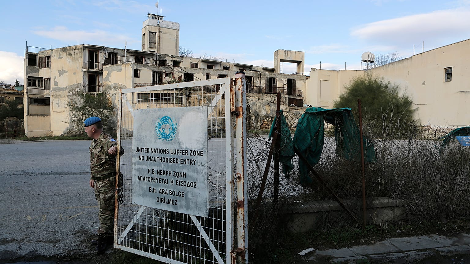 A UN soldier stands by a gate that leads inside the UN buffer zone, Green Line, that divides the Greek, south, and Turkish, north on Jan. 4, 2017. 