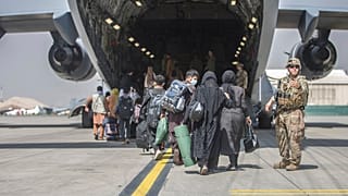 In this image provided by the US Marine Corps, families begin to board a US Air Force plane during an evacuation at Hamid Karzai International Airport, Kabul, August 23, 2021.