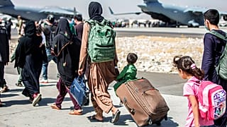 In this image provided by the U.S. Marine Corps, families walk towards their flight during ongoing evacuations at Hamid Karzai International Airport, Kabul,