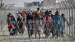 أفغان يسيرون على طول الأسوار عند وصولهم إلى باكستان عبر نقطة العبور الحدودية الباكستانية الأفغانية في شامان، 24 أغسطس 2021