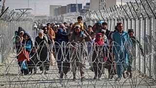 أفغان يسيرون على طول الأسوار عند وصولهم إلى باكستان عبر نقطة العبور الحدودية الباكستانية الأفغانية في شامان، 24 أغسطس 2021