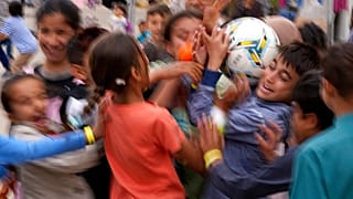 Recently evacuated young Afghans play with a ball at the Ramstein U.S. Air Base, Germany, Tuesday, August 24, 2021.