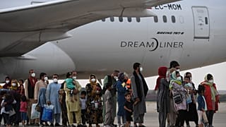Refugees queue on the tarmac after disembarking from an evacuation flight from Kabul, at the Torrejon de Ardoz air base, 30 km from Madrid, on August 24, 2021.