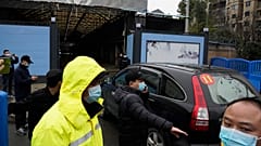 Security personnel clear the way for a convoy of the World Health Organization team to enter the Huanan Seafood Market in Wuhan in January 2021.