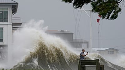 A man takes pictures of high waves along the shore of Lake Pontchartrain as Hurricane Ida nears, Aug. 29, 2021, in New Orleans.