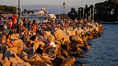 Urlauber sehen sich den Sonnenuntergang in Rovinj an der Adria an