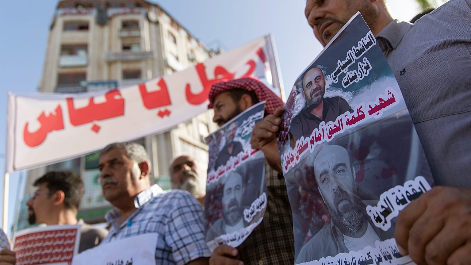 فلسطينيون يقفون بمدينة رام الله يرفعون لافتات تندد بمقتل الناشط نزار بنات على أيدي عناصر من الأجهزة الأمنية الفلسطينية. 03/07/2021