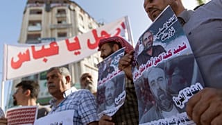 فلسطينيون يقفون بمدينة رام الله يرفعون لافتات تندد بمقتل الناشط نزار بنات على أيدي عناصر من الأجهزة الأمنية الفلسطينية. 03/07/2021