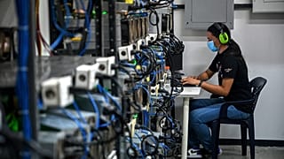An employee inspects computers used to mine Bitcoin at the mining showroom of the Doctor Miner company in Caracas on August 18, 2021.