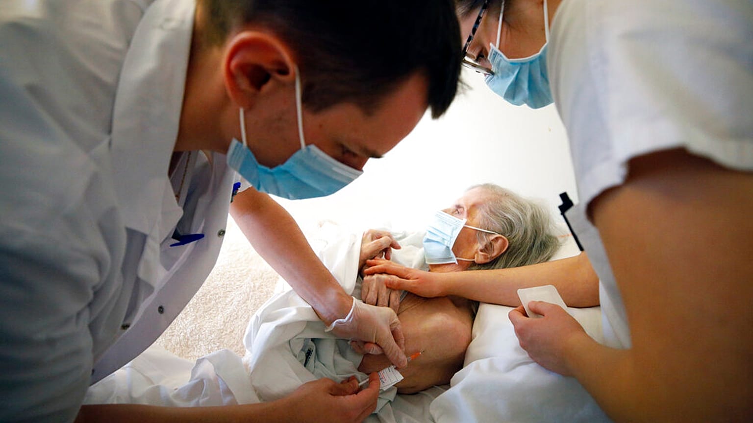 In this Jan. 6, 2021, file photo, Dr. Cedric Waechter, left, administers the Pfizer-BioNTech COVID-19 vaccine to a resident of the Bois Fleuris nursing home in Strasbourg 
